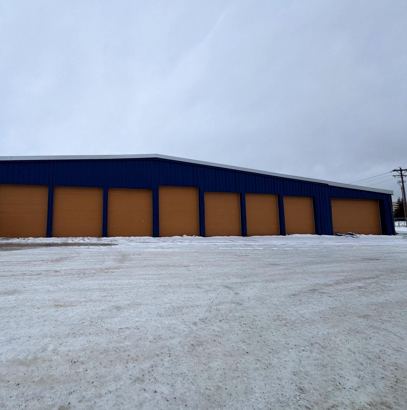Blue warehouse with gold overhead doors at 399 Helmericks